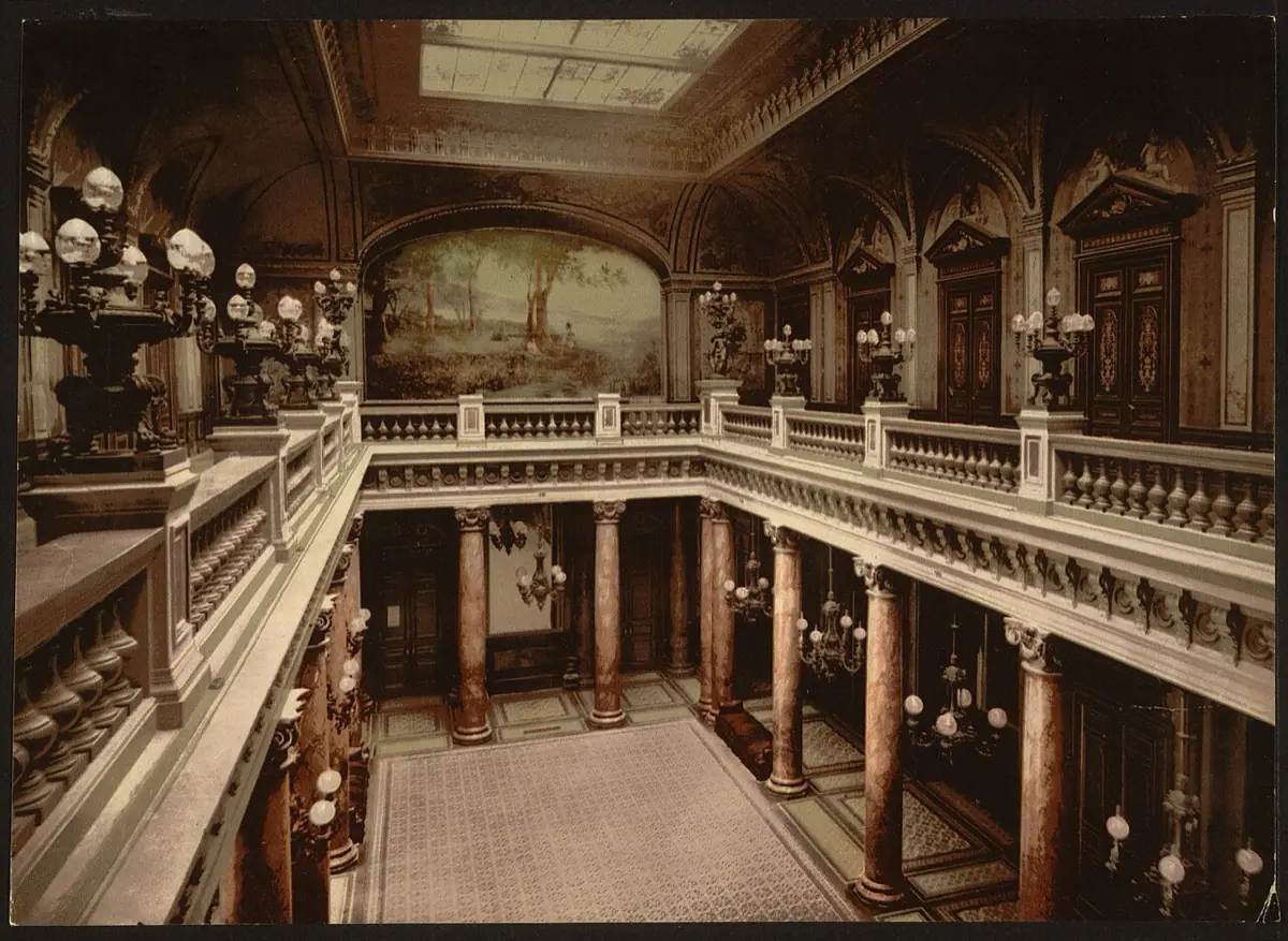 Photochrom print of the Casino de Monte-Carlo entrance atrium in the 1890s, showing the balustraded upper gallery, painted lunette and the doors leading off the hall