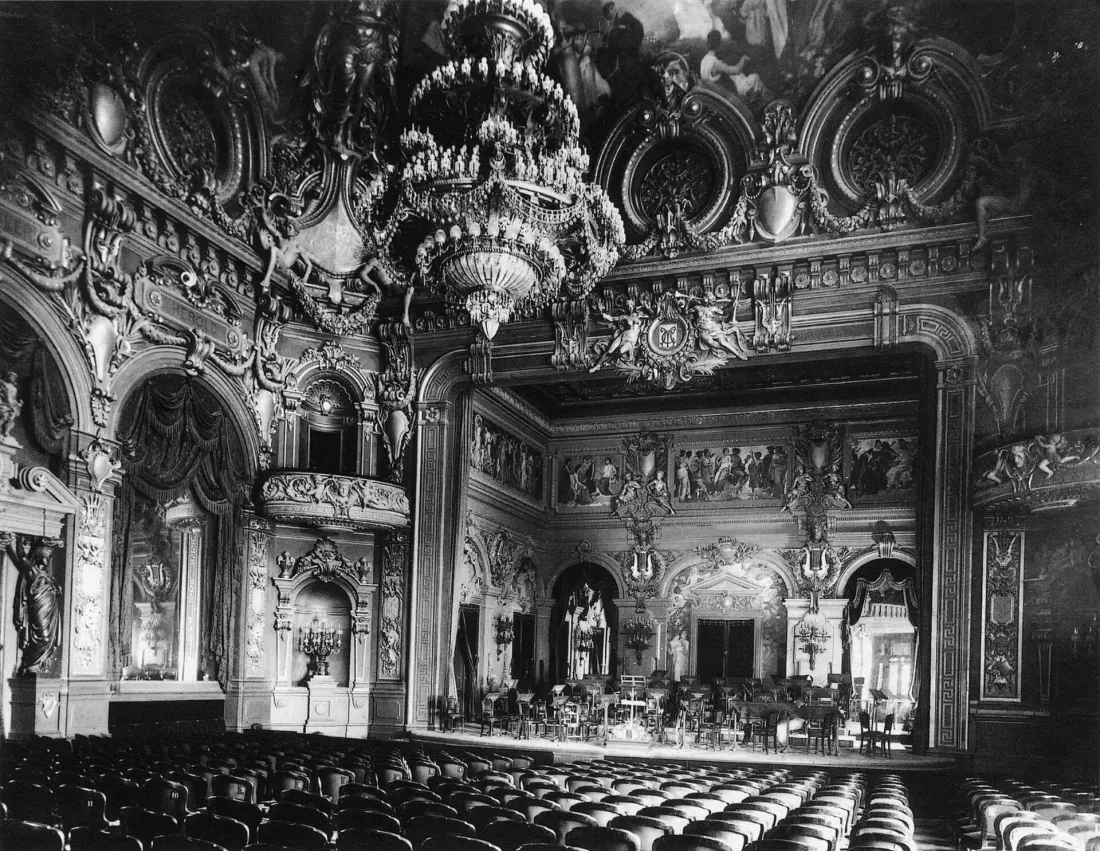 Archival photograph of the Salle Garnier auditorium at the Monte Carlo Casino, tiers of boxes facing a decorated proscenium, taken 1878 to 1879